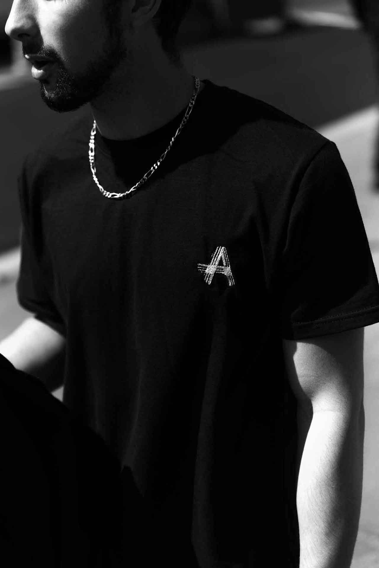 Image de la Collection Just Us d'Amble : T-shirt noir élégant avec le logo distinctif 'A' d'Amble brodé sur le devant. Ce t-shirt incarne le style emblématique de la collection Just Us.
