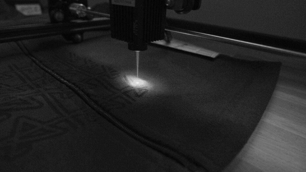 Image du Processus de Marquage au Laser des 'A' sur une Polaire de la Collection Polaire d'Amble : Découvrez la précision du marquage au laser et le souci du détail dans la création de chaque pièce